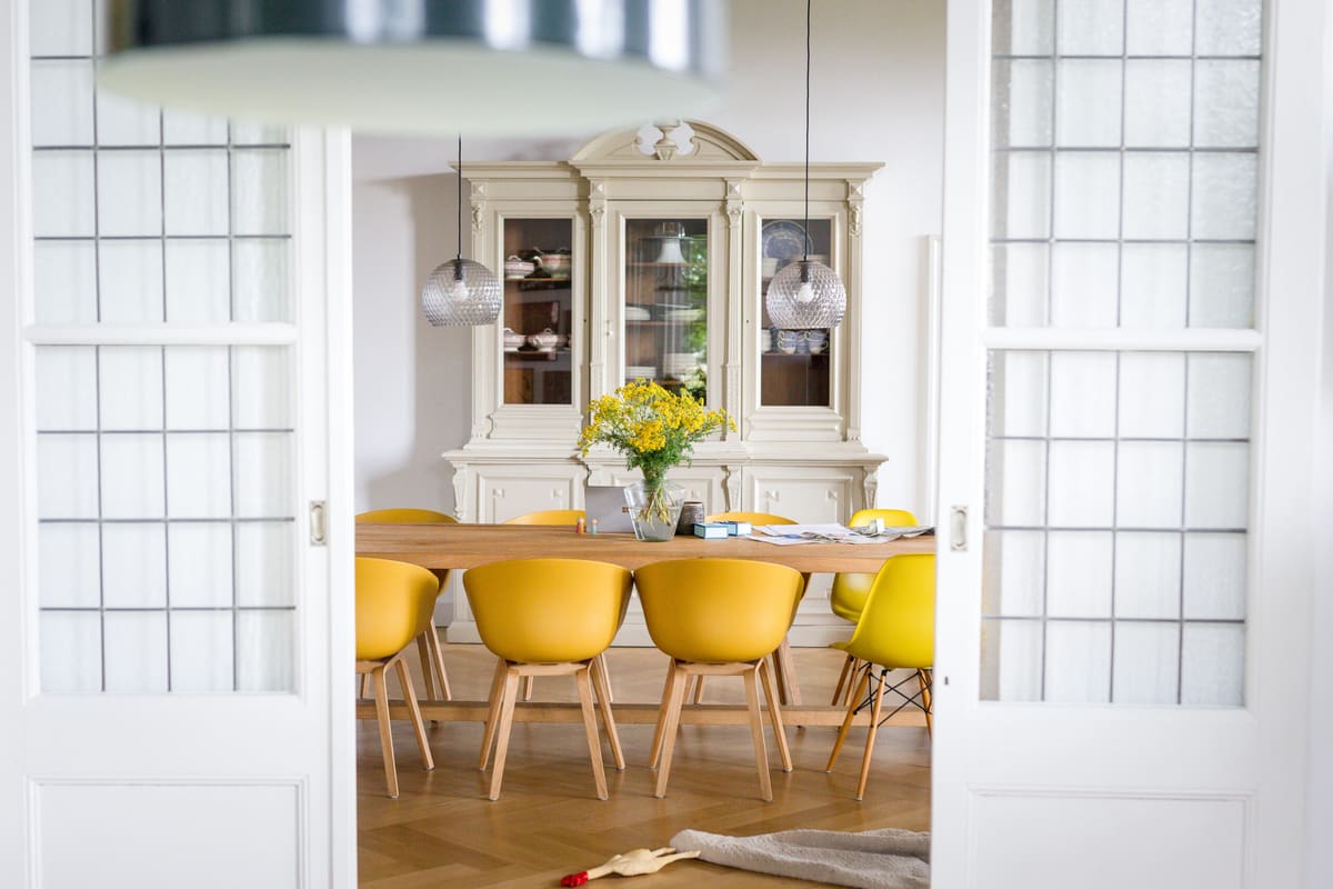 Eetkamer met gele stoelen, houten tafel en klassieke kast voor interieurontwerp en interieurstyling