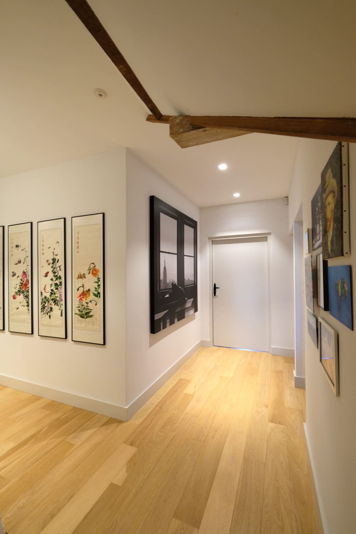 Interieurontwerp en interieurstyling van hal met kunst, houten balken en lichte vloer