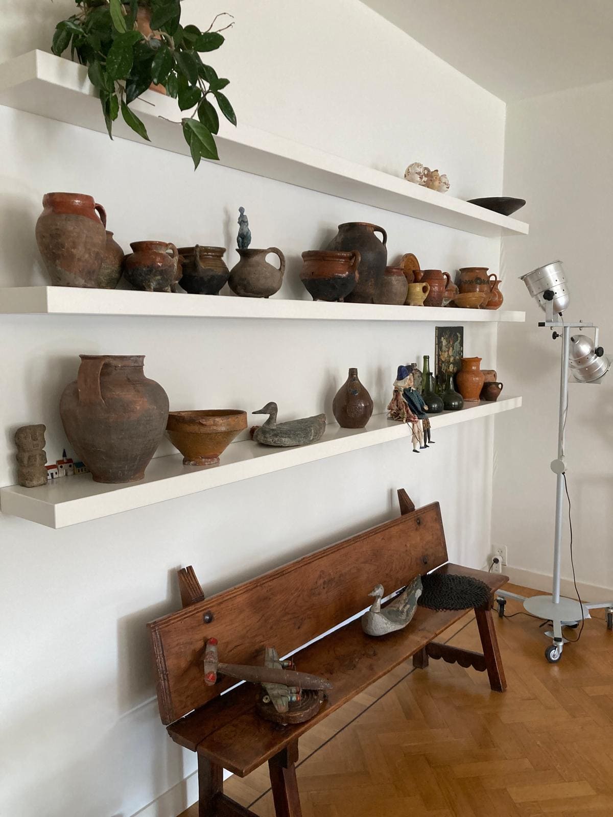 Interieurstyling met open planken, aardewerk en houten bank in persoonlijk interieur
