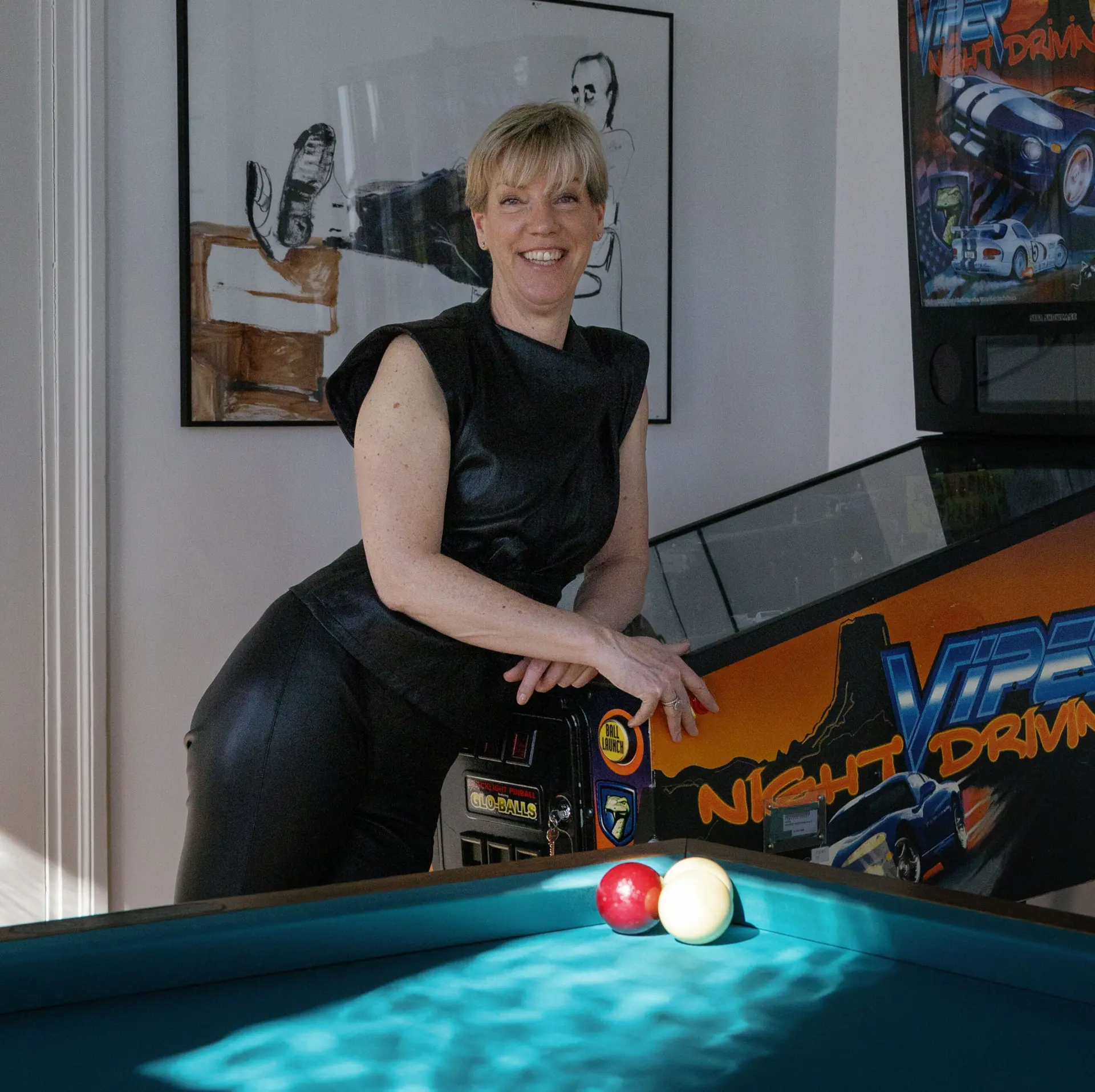 Kirsten Hermsen leunt op een biljarttafel in een kleurrijk interieur